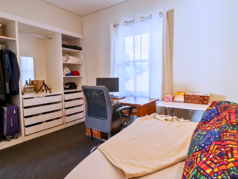 A functional bedroom featuring extensive built-in cabinetry, including a wardrobe, shelving, and drawers, providing ample storage space.