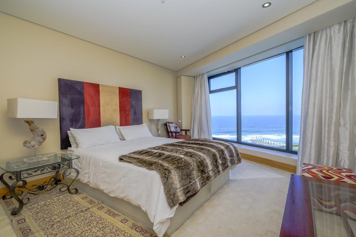 Spacious bedroom featuring large floor-to-ceiling windows with expansive ocean views and neutral finishes.