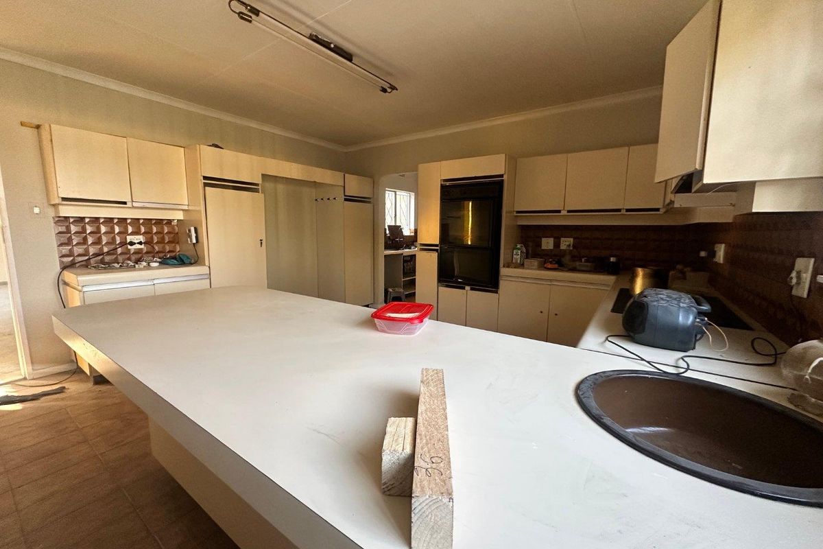 A dated kitchen featuring built-in cabinetry, an integrated oven, and a large central island with a sink, offering significant potential for modern renovation.