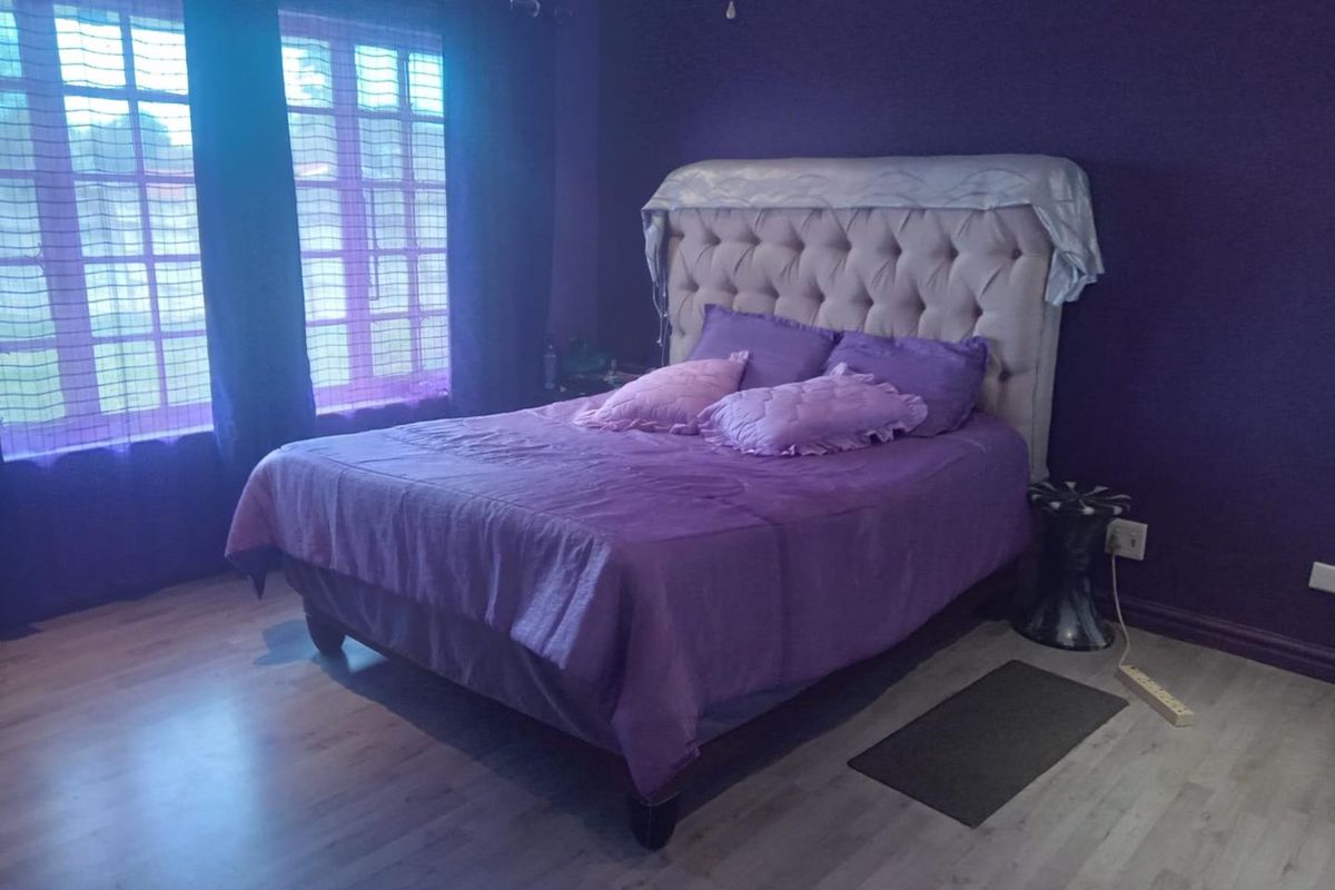 A bedroom featuring laminate flooring and large french windows, providing natural light and a spacious feel.