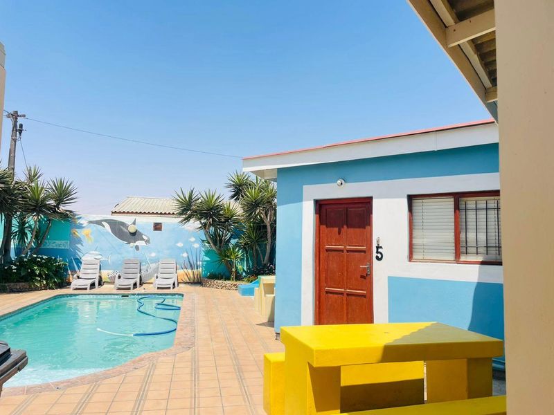 Outdoor pool area featuring a tiled patio, swimming pool, and a painted boundary wall with mural art.