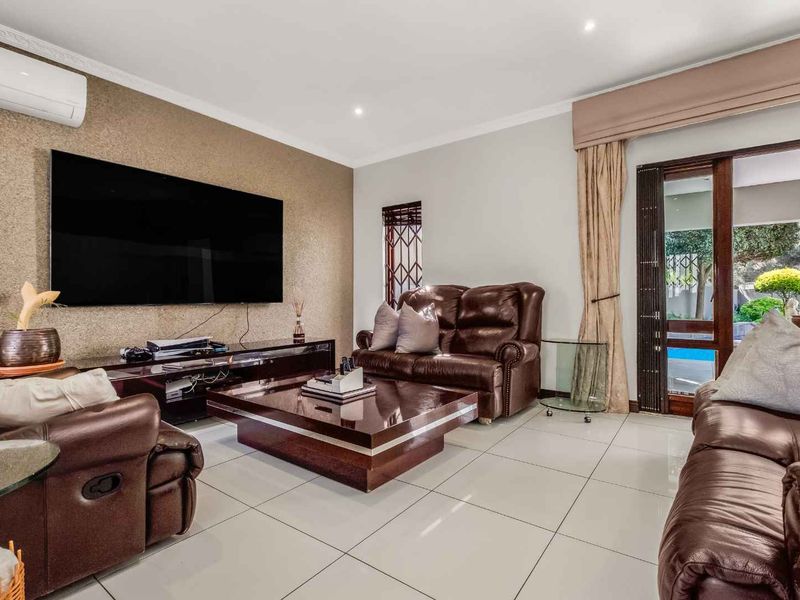 Spacious living room featuring large format floor tiles, a textured feature wall, split-system air conditioning, and direct access to the outdoor pool area.