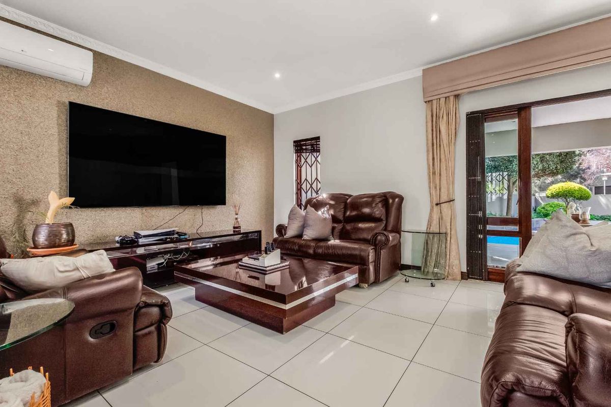 Spacious living room featuring large format floor tiles, a textured feature wall, split-system air conditioning, and direct access to the outdoor pool area.