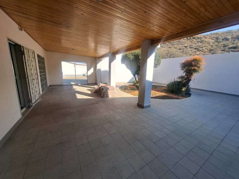 A spacious covered patio featuring a timber-clad ceiling, tiled flooring, and direct access to a private garden area with boundary walls.