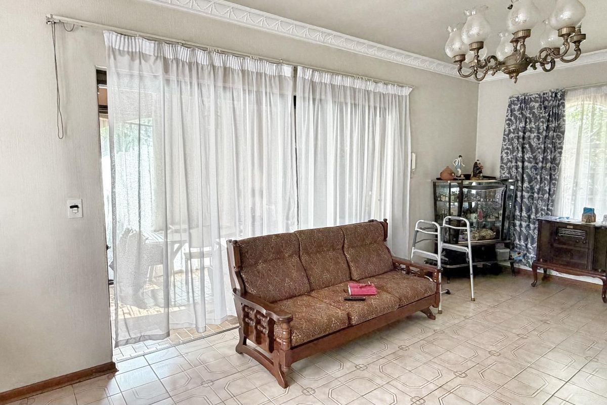 A living room featuring tiled flooring, decorative ceiling cornices, and large sliding glass doors providing access to the outdoor patio area.