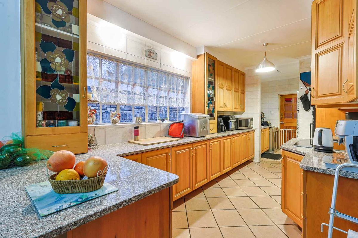 A functional kitchen featuring warm wooden cabinetry, granite countertops, tiled flooring, and decorative stained glass cabinet accents.