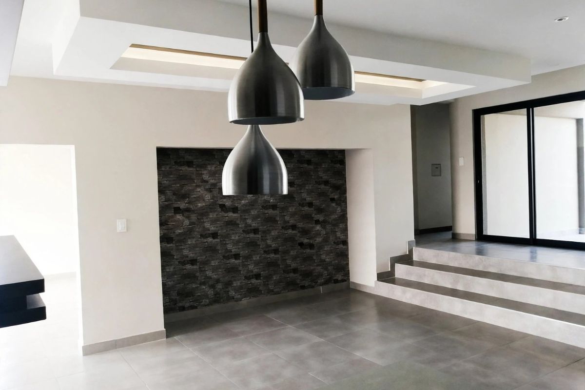 Modern living area featuring a recessed ceiling, stone accent wall, tiled flooring, and a stepped transition leading to a sliding glass door.