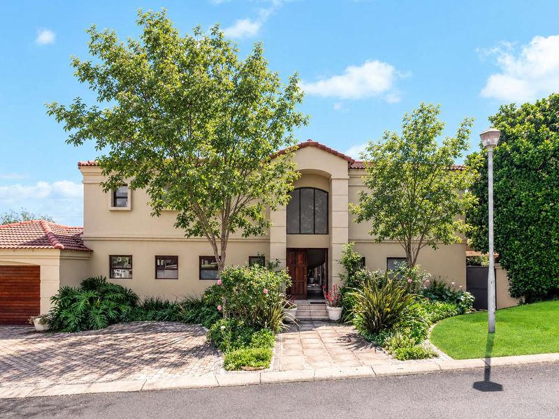 A well-maintained double-story residence featuring a paved driveway, arched entrance, and established garden with a tiled roof.