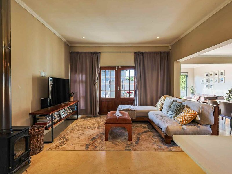 Spacious living area featuring polished concrete floors, a freestanding fireplace, and direct access to the outdoors through classic timber french doors.