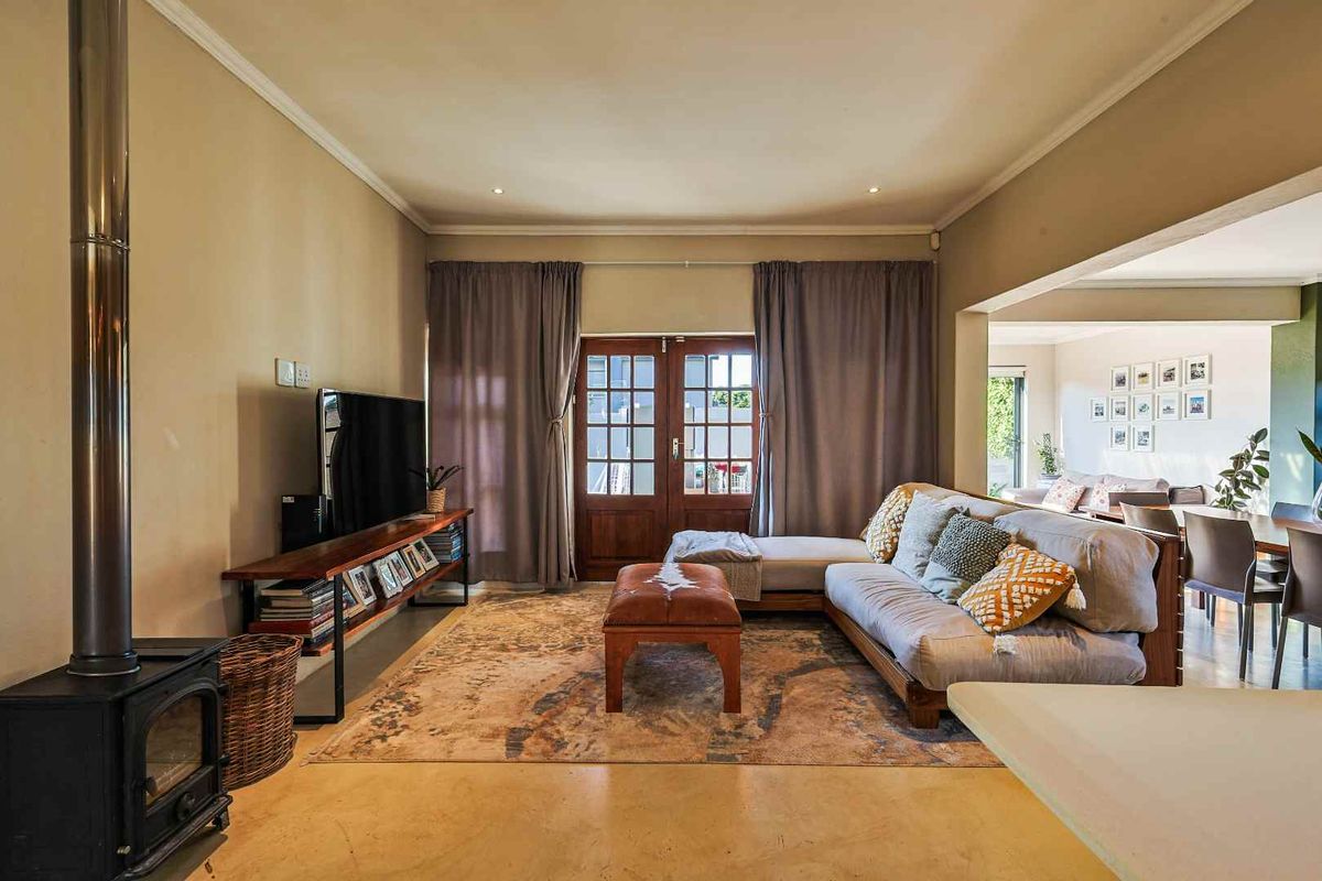 Spacious living area featuring polished concrete floors, a freestanding fireplace, and direct access to the outdoors through classic timber french doors.