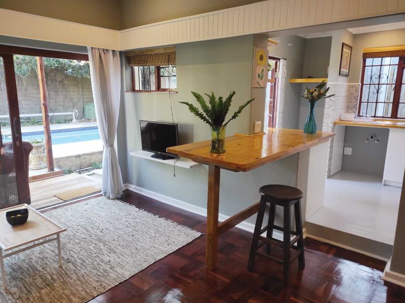 Open-plan living area featuring warm parquet flooring, a breakfast bar, and direct access to the outdoor pool area through sliding glass doors.