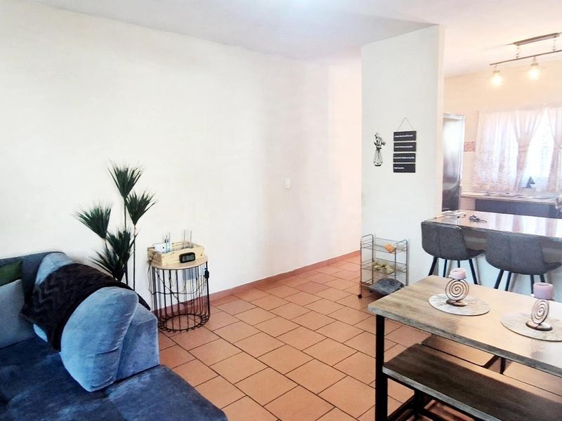 Open plan living and dining area featuring tiled flooring and a breakfast bar connecting to the kitchen space.