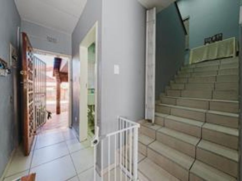 Entrance hall featuring tiled flooring, a solid wood front door with security gate, and a tiled staircase leading to the upper level.