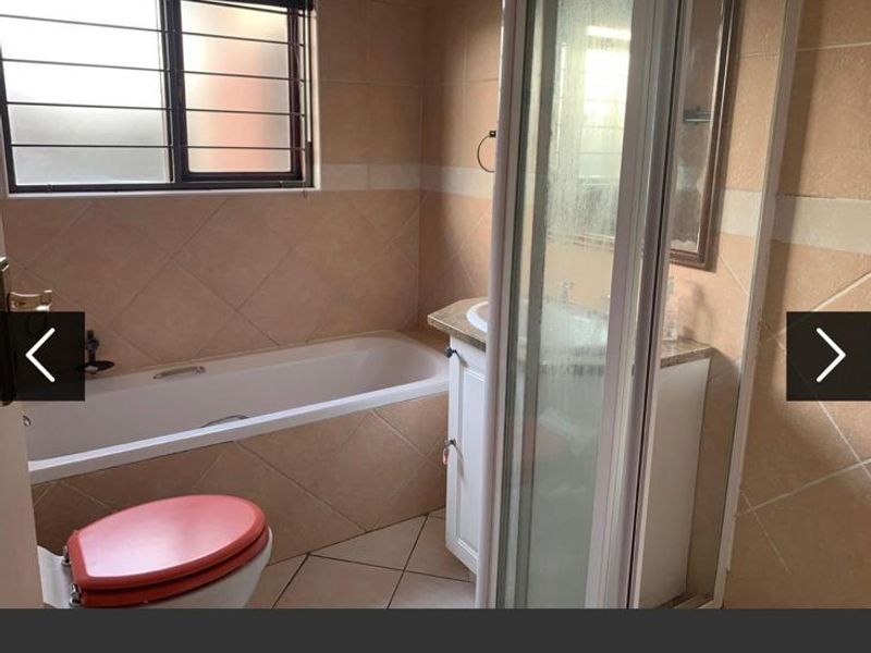 A functional bathroom featuring a built-in bathtub, a separate shower enclosure, and a vanity cabinet with tiled finishes throughout.