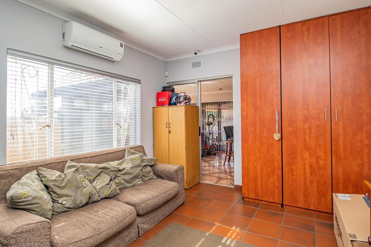 Bedroom featuring terracotta floor tiles, a built-in wardrobe, and a wall-mounted split-system air conditioner.