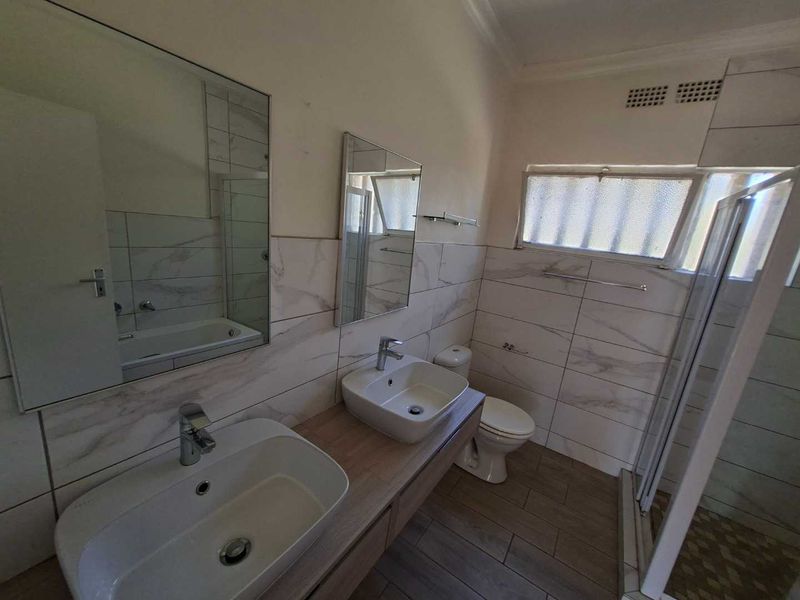 Modern bathroom featuring a double vanity with vessel sinks, a separate shower enclosure, a bathtub, and contemporary wall and floor tiling.