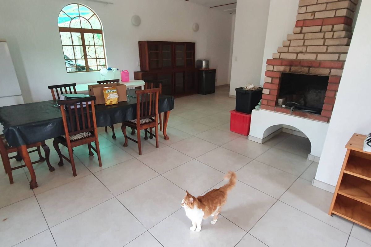 Spacious living area featuring a prominent brick fireplace, tiled flooring, and an arched window, offering a versatile layout for dining and relaxation.