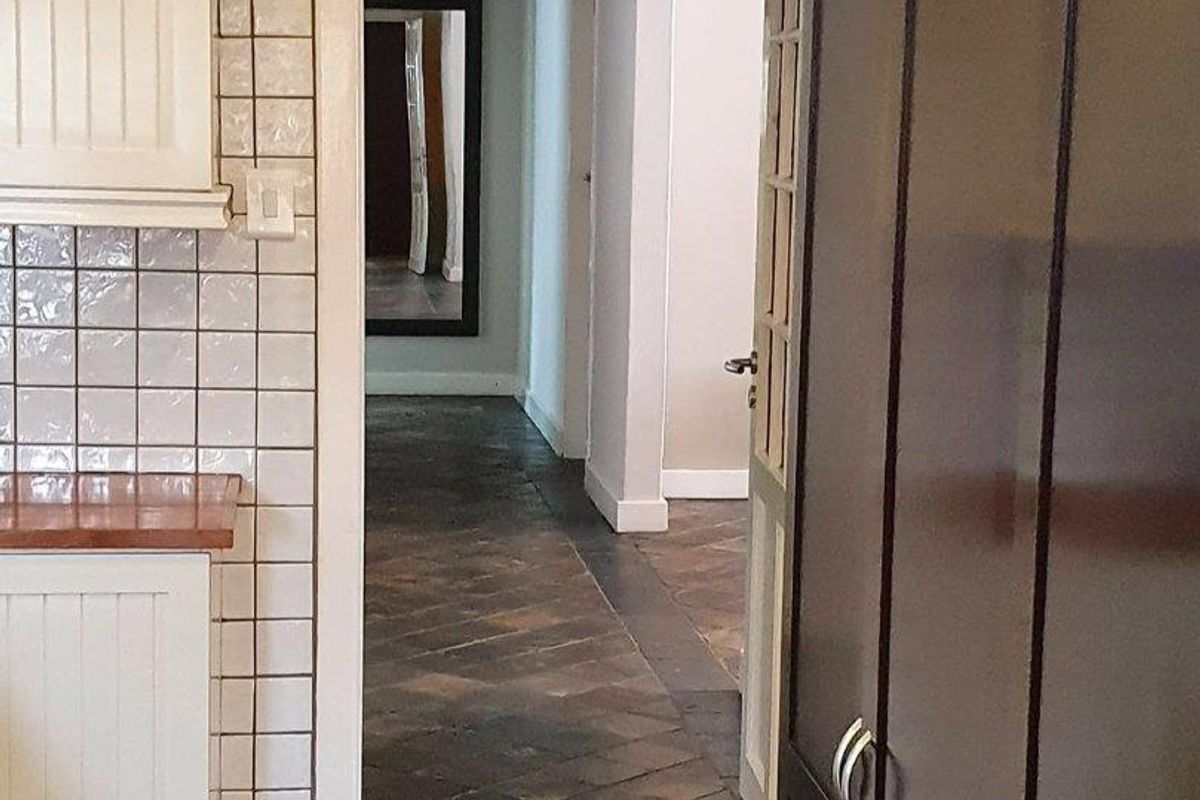 A view from the kitchen into a hallway featuring dark slate-style floor tiles and built-in cabinetry.