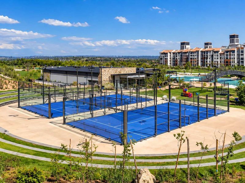 Well-maintained outdoor padel courts set within a landscaped recreational area, featuring modern floodlighting and paved surroundings.