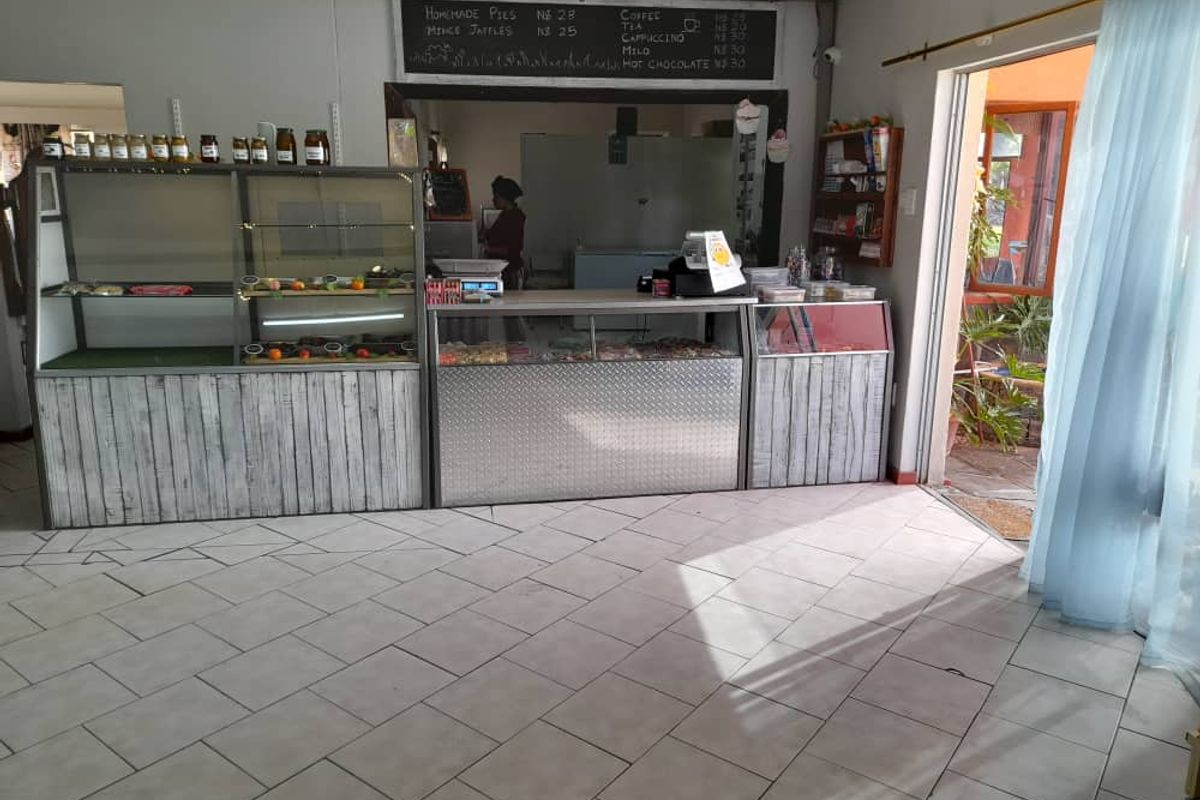 A commercial service area featuring built-in display counters, a service hatch, and tiled flooring, suitable for a farm shop or cafe setup.