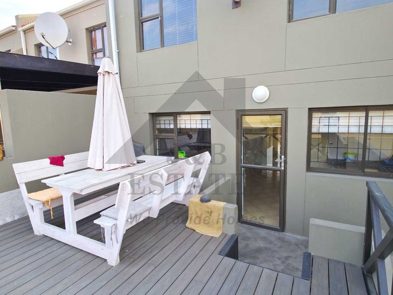 A private timber deck patio area featuring direct access to the townhouse interior through a security door and sliding windows.