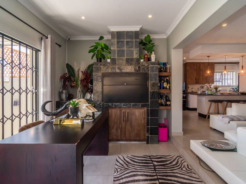 Open-plan living area featuring a built-in stone-clad fireplace and seamless flow into the adjacent kitchen with breakfast bar.