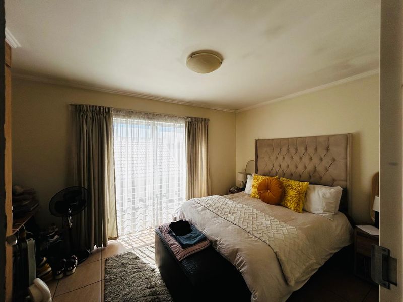 A well-lit bedroom featuring tiled flooring and a large sliding glass door that provides access to the exterior.