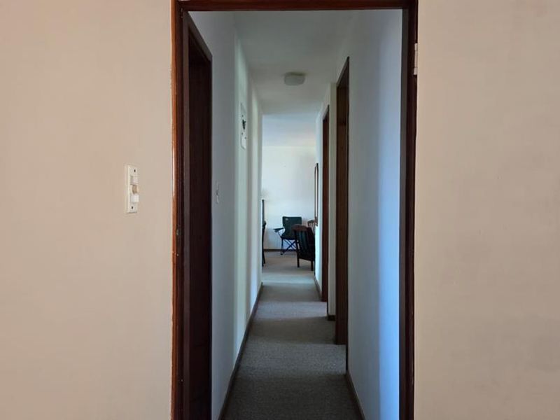 A functional hallway featuring timber door frames, a transom window above the doorway, and carpeted flooring connecting the interior spaces.