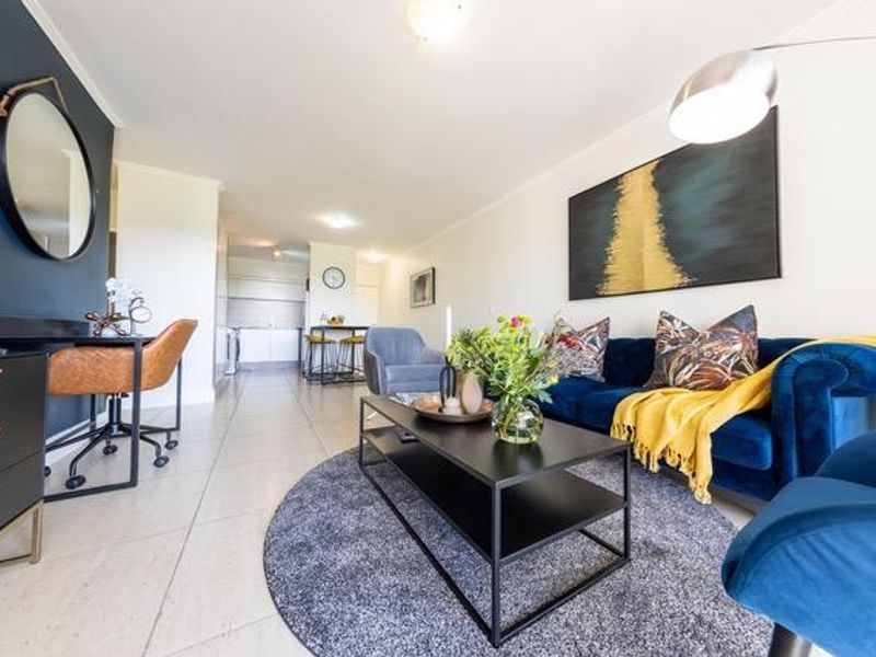 A bright open-plan living area featuring tiled flooring, modern finishes, and a seamless transition into the kitchen space.