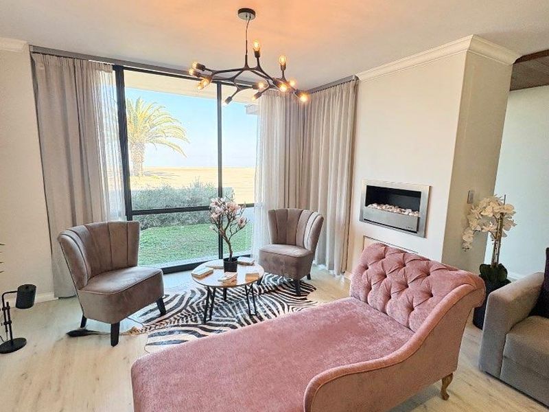 A bright living room featuring a modern built-in fireplace, large sliding glass doors with garden views, and contemporary light-toned laminate flooring.