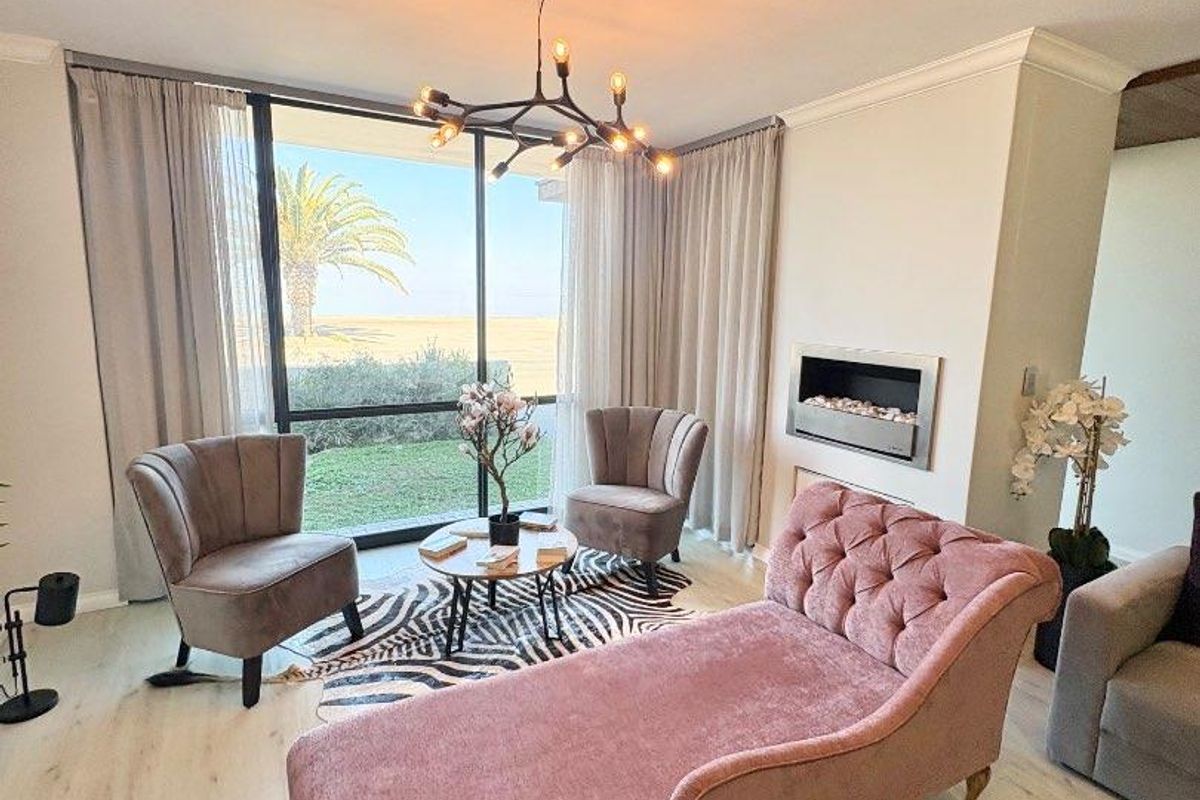 A bright living room featuring a modern built-in fireplace, large sliding glass doors with garden views, and contemporary light-toned laminate flooring.