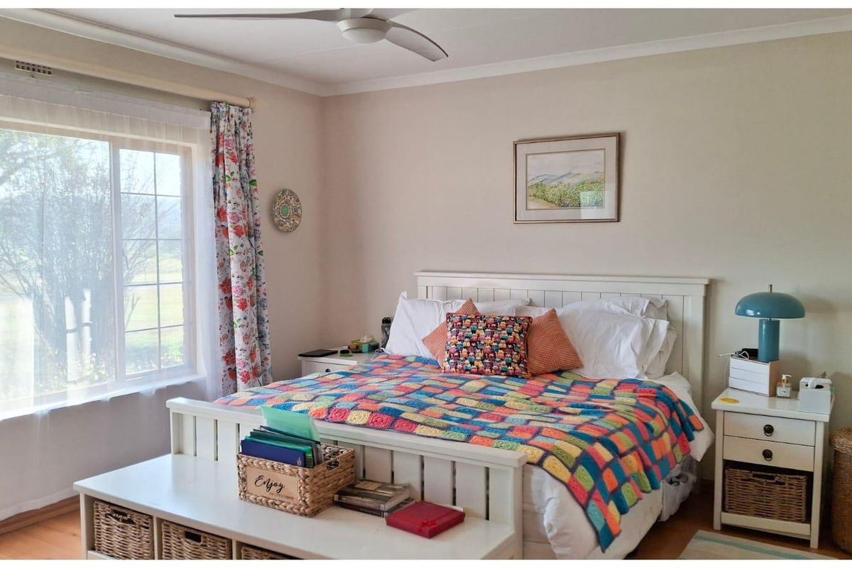 A well-maintained bedroom featuring laminate flooring, a ceiling fan, and a large sliding window providing natural light.