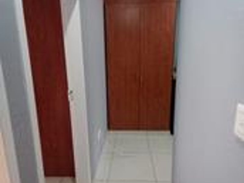 A functional hallway featuring tiled flooring and built-in wooden cupboards for storage.