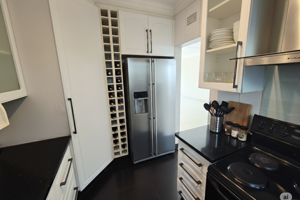 Modern kitchen featuring black granite countertops, white cabinetry, built-in wine rack, and stainless steel side-by-side refrigerator.