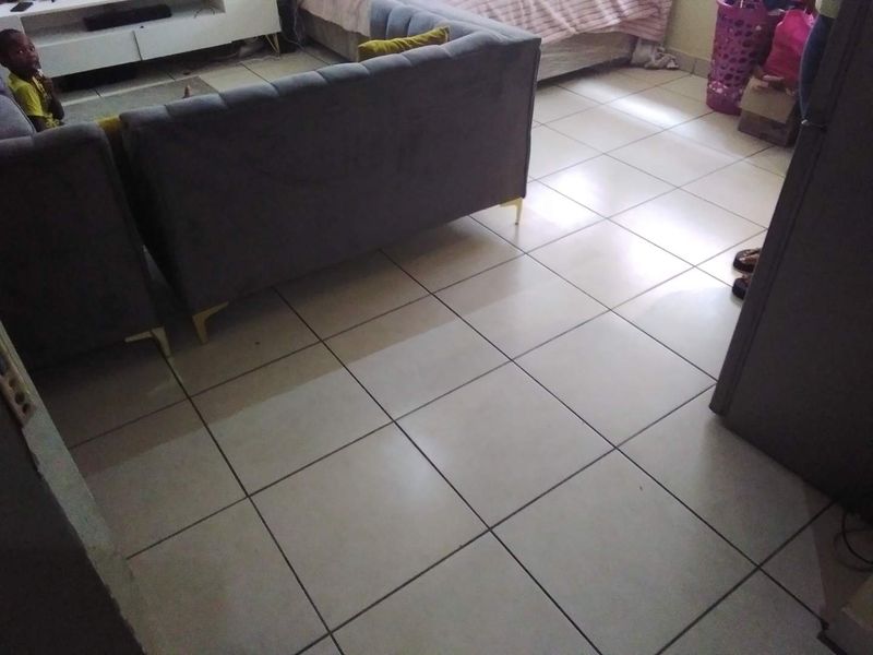 A living area featuring neutral ceramic floor tiles throughout, providing a functional and clean base for the space.