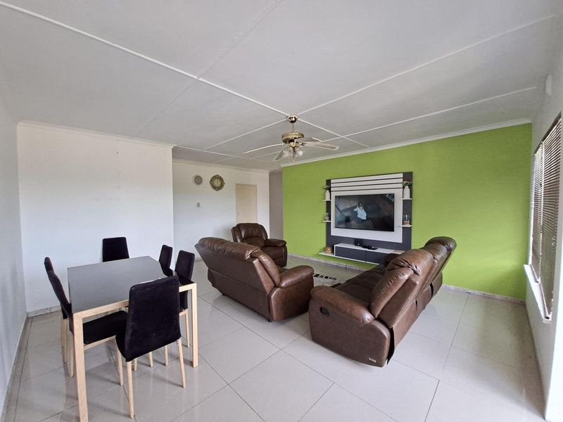 Open-plan living and dining area featuring tiled flooring, a ceiling fan, and a built-in media wall unit.