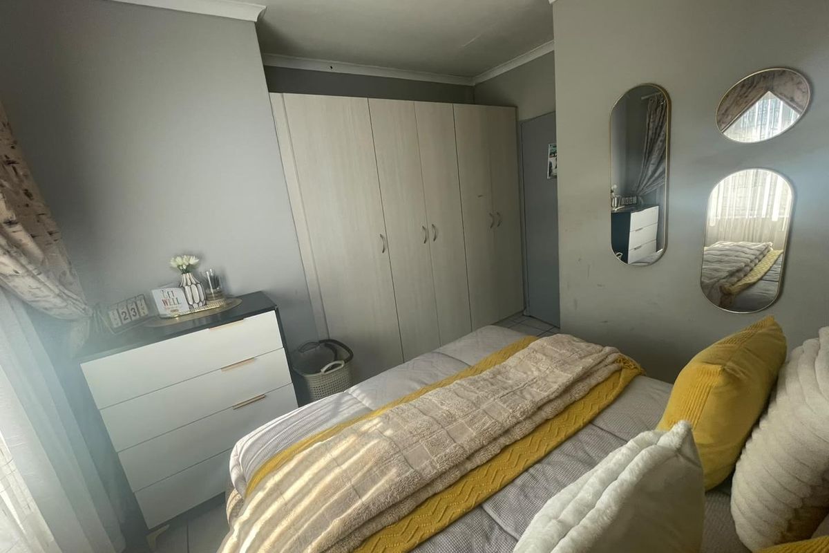 A functional bedroom featuring built-in cupboards, tiled flooring, and neutral wall finishes, providing a practical living space.