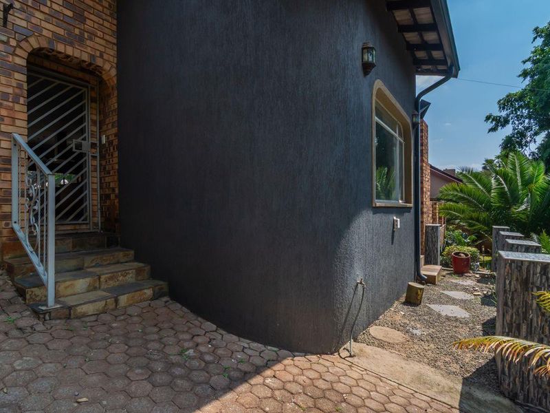 Front entrance area featuring a combination of brick and dark textured render, stone steps, and paved access path.