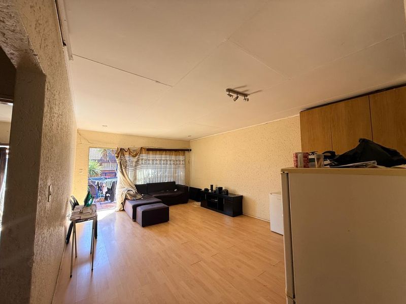 Open-plan living area featuring laminate flooring, textured walls, and ceiling track lighting, with direct access to an outdoor patio area.