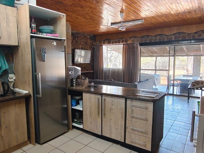 Open-plan kitchen and living area featuring wood-paneled ceilings, stone accent walls, and direct access to an outdoor patio through sliding glass doors.