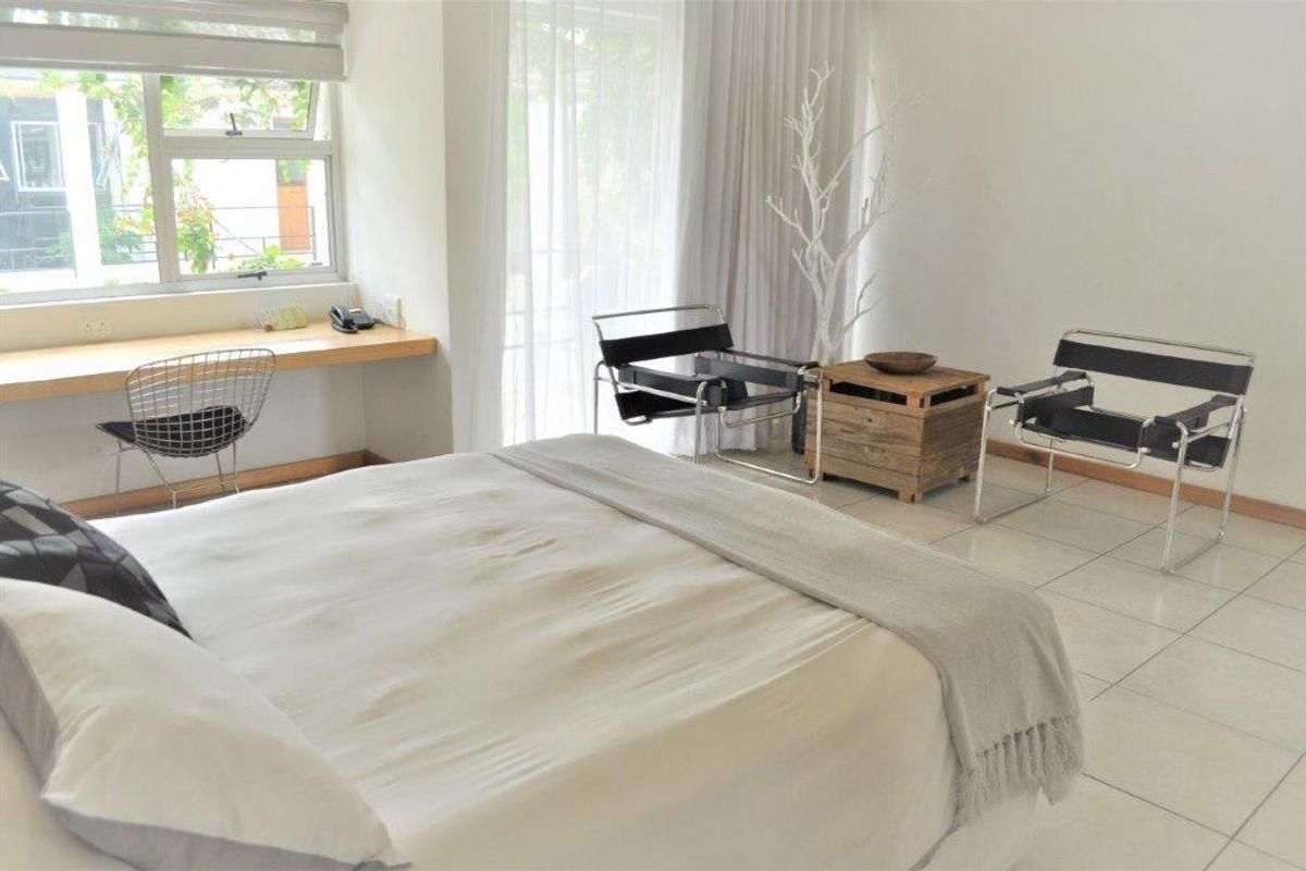 Spacious bedroom featuring tiled flooring, a built-in desk area, and large windows with access to a patio through sliding glass doors.