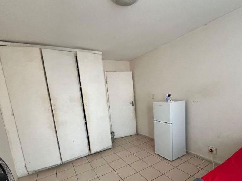 A bedroom featuring built-in cupboards and tiled flooring, requiring cosmetic updates to the wall finishes and cabinetry to improve its overall condition.