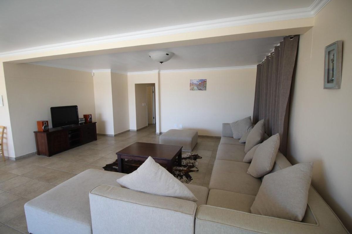 Spacious living area featuring neutral tiled flooring, recessed ceiling details, and a functional layout suitable for comfortable relaxation.