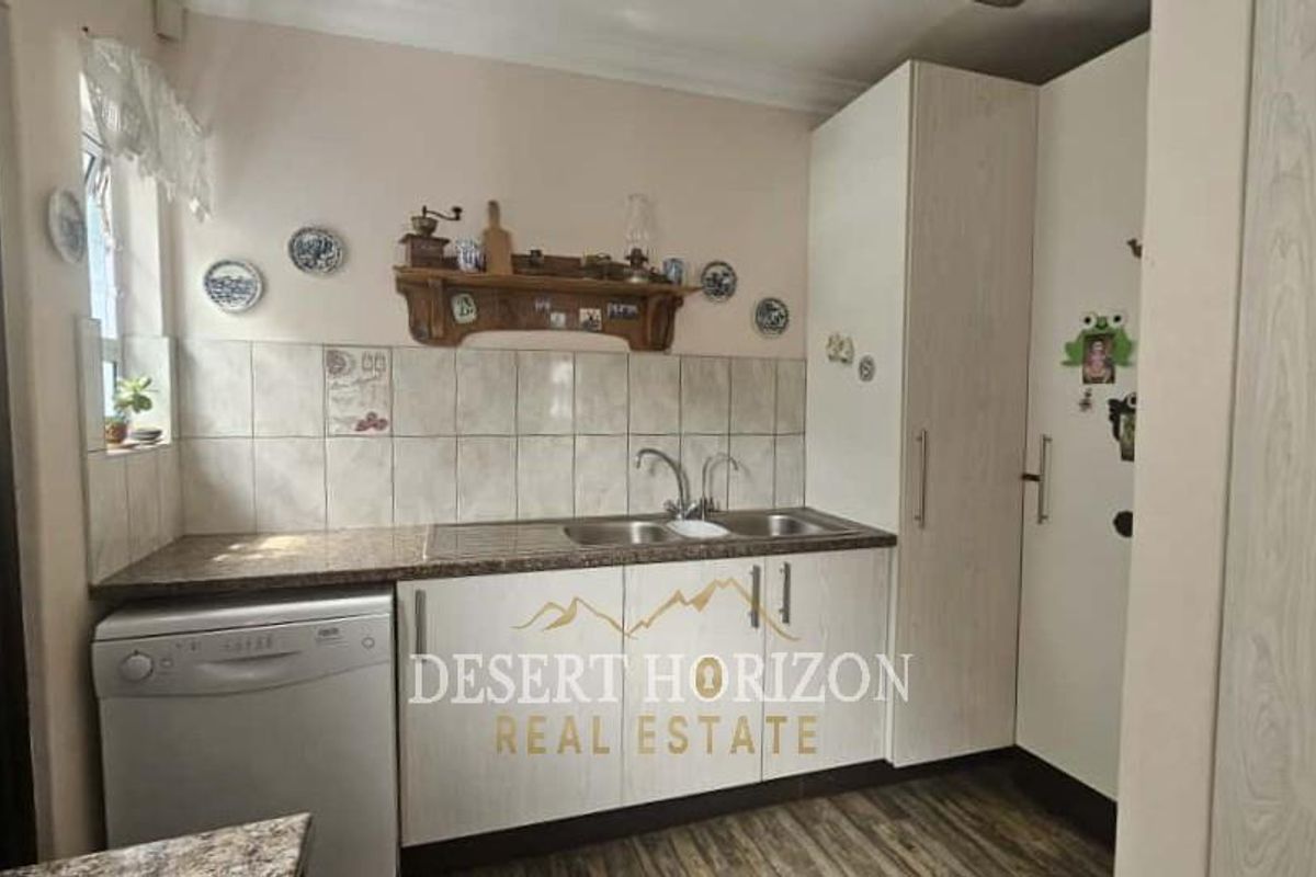 A functional kitchen area featuring built-in cabinetry, a double sink, tiled splashbacks, and space for a dishwasher.