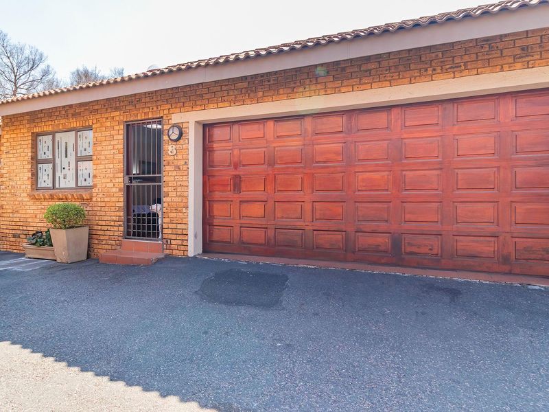 Front exterior view of the property featuring a face-brick facade, a large sectional garage door, and a secure pedestrian entrance.