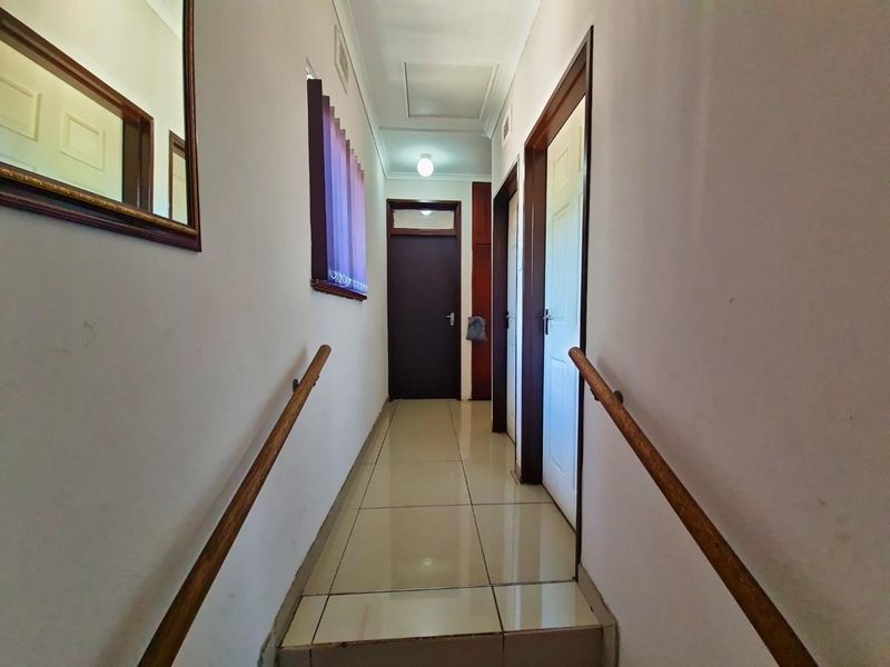A functional hallway featuring tiled flooring and wooden handrails, providing access to multiple rooms within the home.