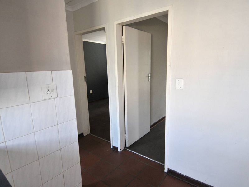 A functional hallway area featuring tiled flooring and access to multiple rooms, presenting a blank canvas for potential interior updates.