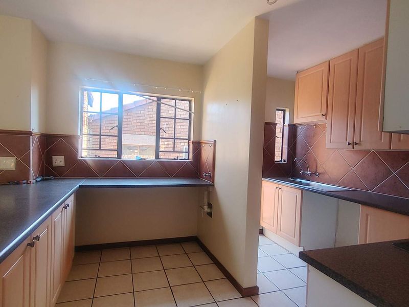 A functional kitchen featuring laminate cabinetry, dark countertops, tiled backsplash, and ceramic flooring, offering a clean, blank canvas for potential modern updates.