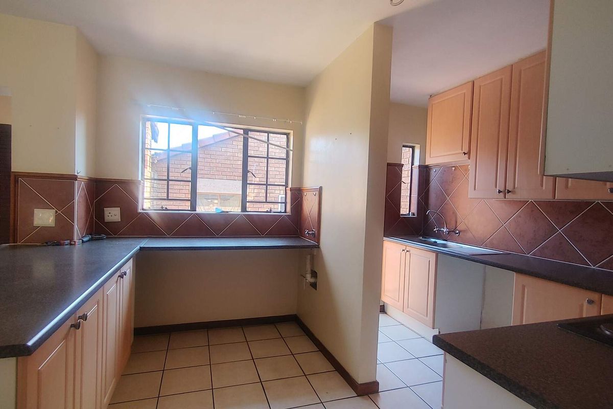 A functional kitchen featuring laminate cabinetry, dark countertops, tiled backsplash, and ceramic flooring, offering a clean, blank canvas for potential modern updates.