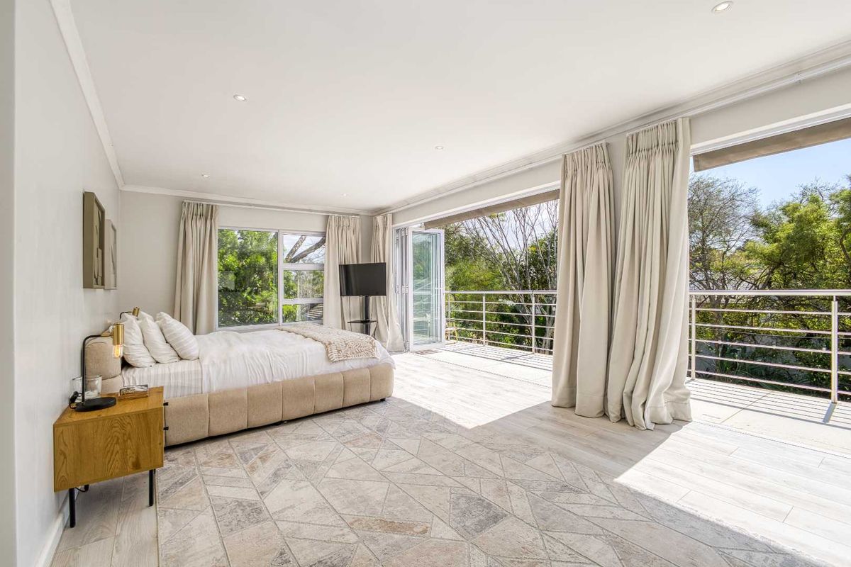 Spacious bedroom featuring large bi-fold doors opening onto a private balcony with a metal balustrade and modern tiled flooring.